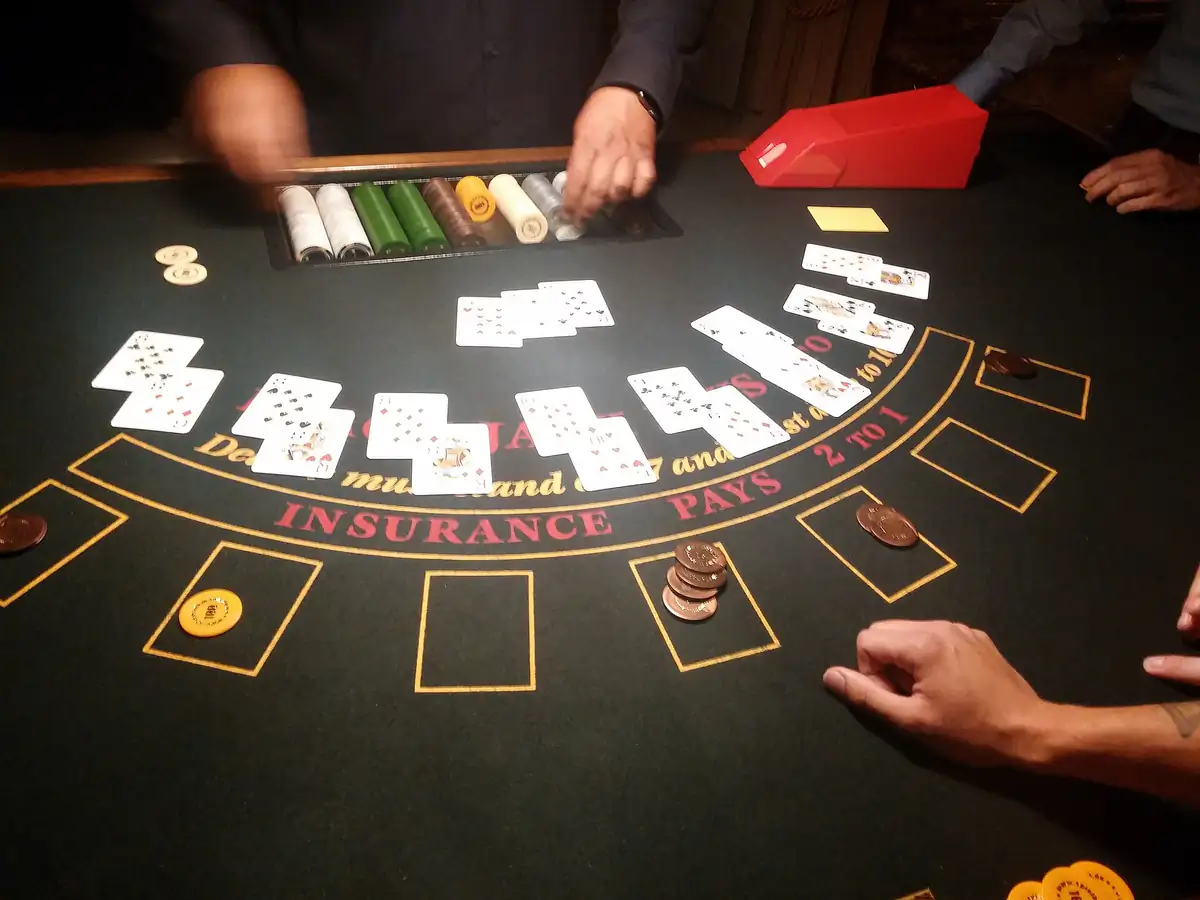 Az osztó lapokat oszt egy blackjackasztalon, a játékosok zsetonjai a mezőkben